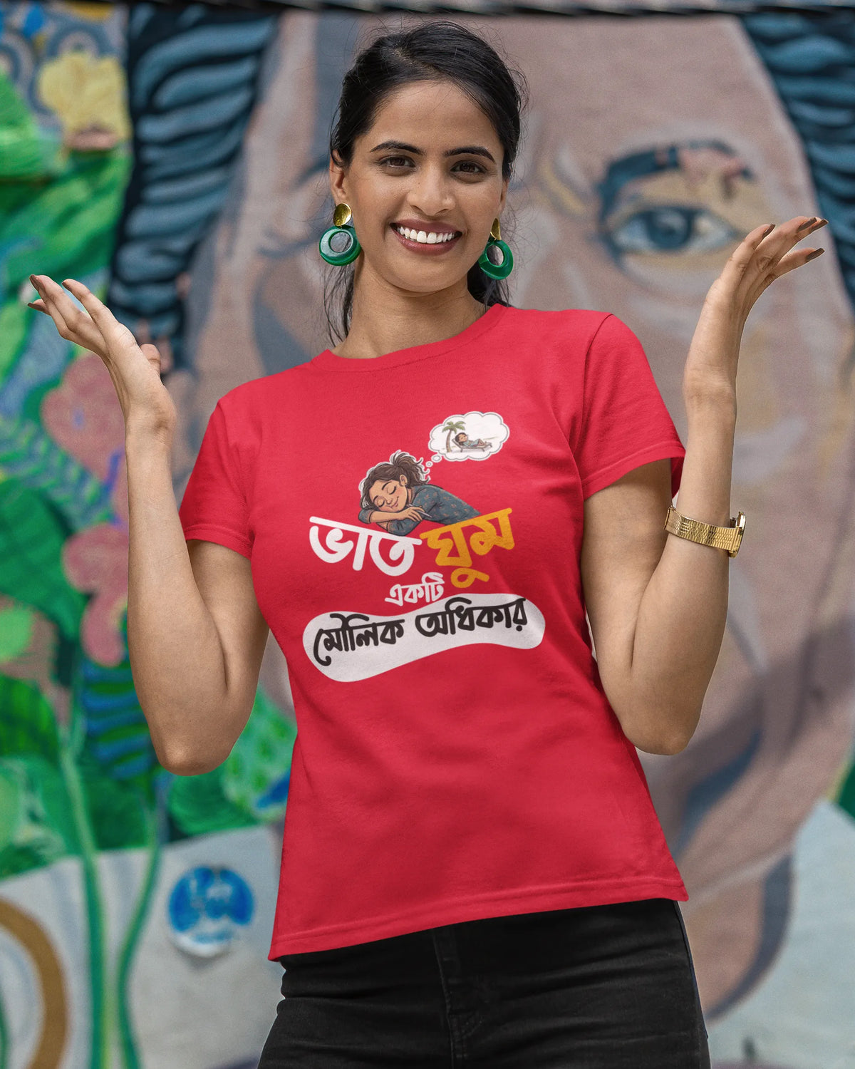 A woman posing in front of a colorful mural wearing a red graphic t-shirt with Bengali text and a cartoon character, paired with black pants.
