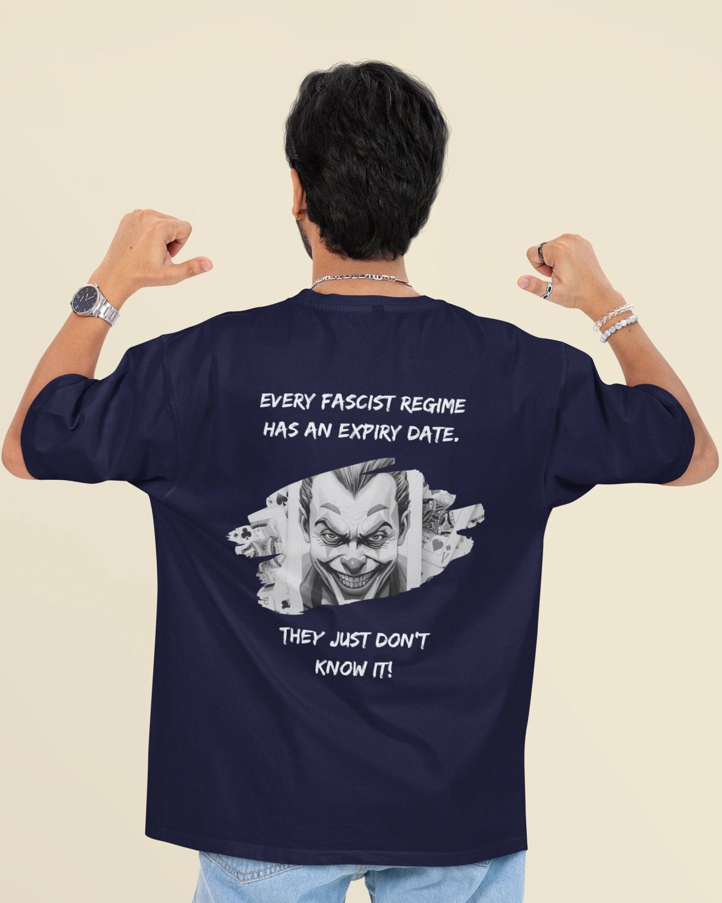 A man viewed from behind wearing a navy blue t-shirt with a white graphic of a clown face and the text 'EVERY FASCIST REGIME HAS AN EXPIRY DATE. THEY JUST DON'T KNOW IT!'.