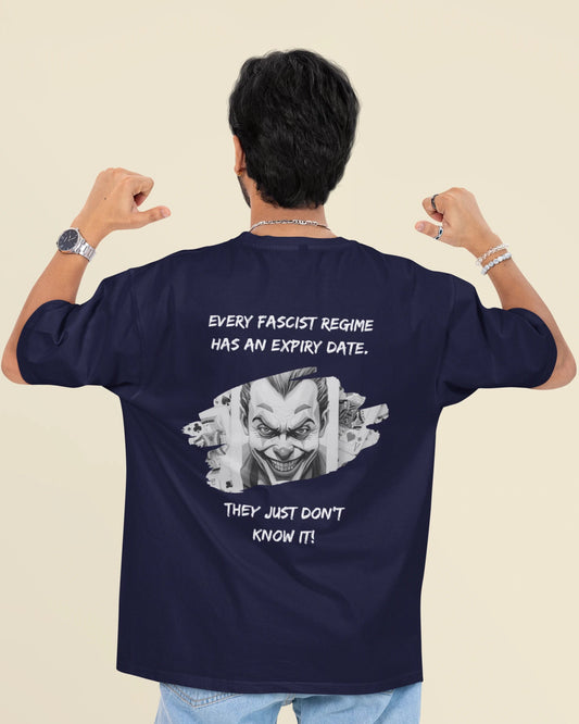 A man viewed from behind wearing a navy blue t-shirt with a white graphic of a clown face and the text 'EVERY FASCIST REGIME HAS AN EXPIRY DATE. THEY JUST DON'T KNOW IT!'.