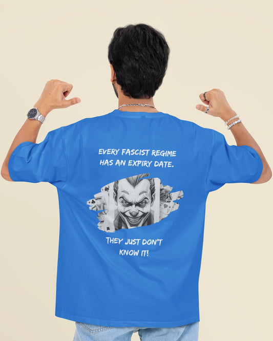A man viewed from behind wearing a bright blue t-shirt with a large graphic print on the back. The graphic features a stylized clown face with the text 'EVERY FASCIST REGIME HAS AN EXPIRY DATE.