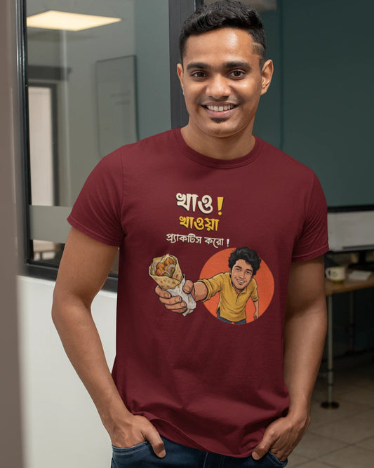 A smiling man wearing a "Bong Cazuals" graphic t-shirt featuring Bengali typography and an illustrated character offering a food roll, shot in an indoor office or lifestyle setting.