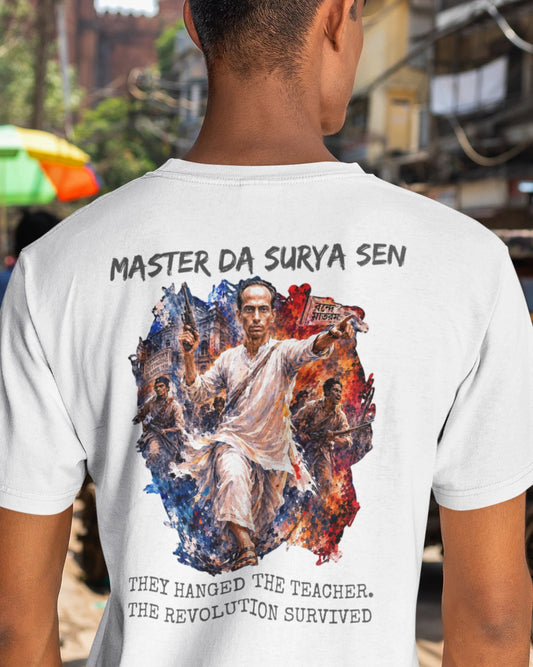 A man viewed from behind wearing a white t-shirt with a large graphic print on the back. The graphic features the text 'MASTER DA SURYA SEN' at the top and 'THEY HANGED THE TEACHER, THE REVOLUTION SURVIVED' at the bottom, surrounding an artistic depiction of a revolutionary figure.