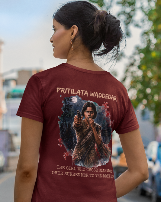 A woman shown from behind wearing a maroon short-sleeve t-shirt with a large graphic print on the back. The graphic features the text 'PRITILATA WADDEDAR' and 'THE GIRL WHO CROSSED OVER SURRENDER TO THE BATTLE' surrounding an illustration of a woman holding a gun.