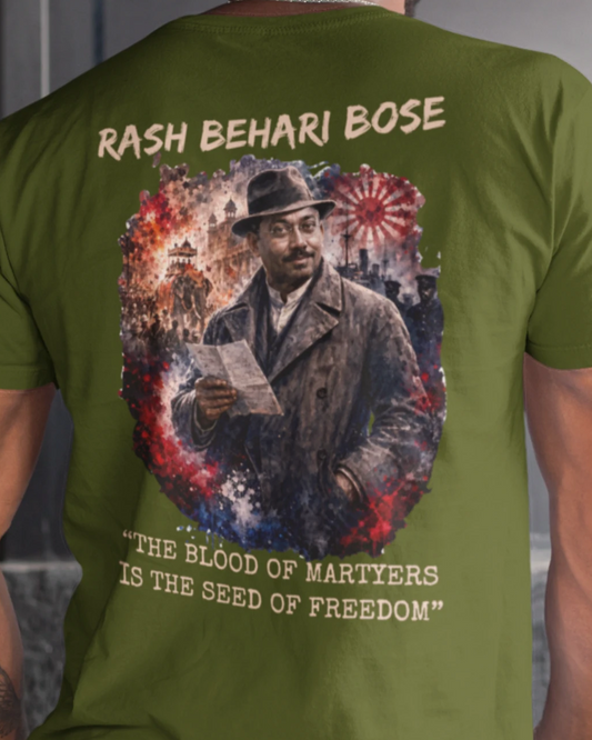 An olive green short-sleeve t-shirt shown from the back on a model, featuring a large graphic print of Rash Behari Bose with the text 'RASH BEHARI BOSE' and 'THE BLOOD OF MARTYRS IS THE SEED OF FREEDOM'.
