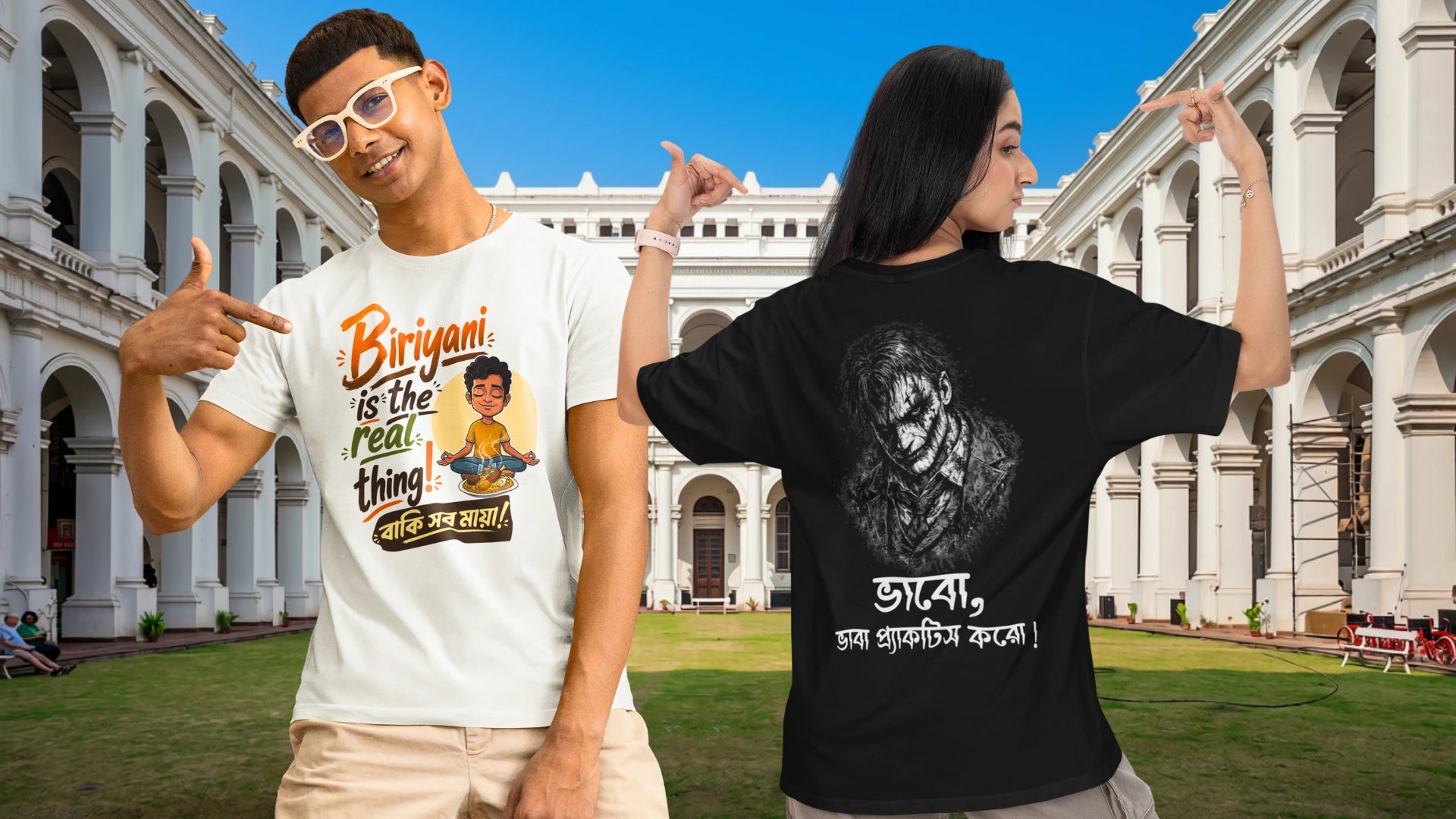 Two models posing in front of a grand classical building, showcasing matching graphic t-shirts. The model on the left wears a white t-shirt with a colorful cartoon graphic and Bengali text, while the model on the right wears a black t-shirt showing the back design with a grayscale portrait and Bengali text.