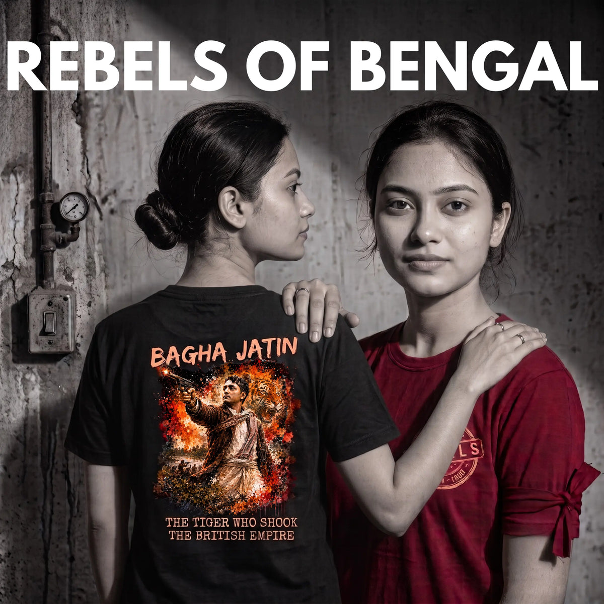 Two women standing side by side against a textured gray wall. The woman on the left wears a black graphic T-shirt with the text 'BAGHA JATIN' and a fiery tiger print, while the woman on the right wears a red T-shirt.